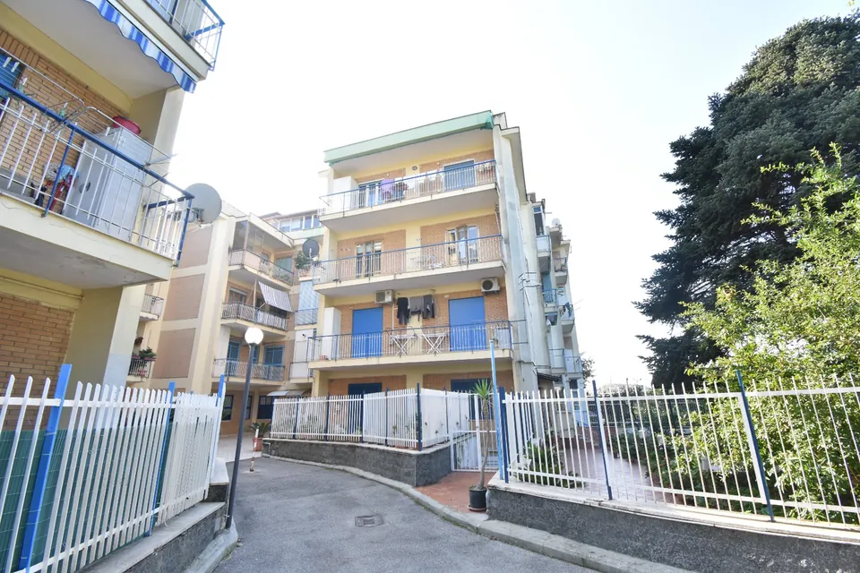 Le palazzine di un condominio viste dal cortile interno, con i balconi in fila, le ringhiere e il vialetto d'ingresso